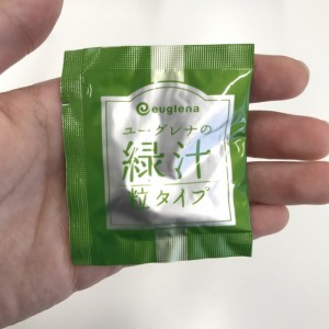 ユーグレナの緑汁粒タイプの粒が個包装されている袋を紹介しているところ