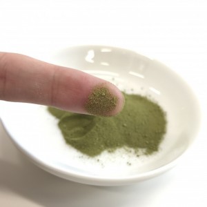 ユーグレナの緑汁の粉末を指についけているところ